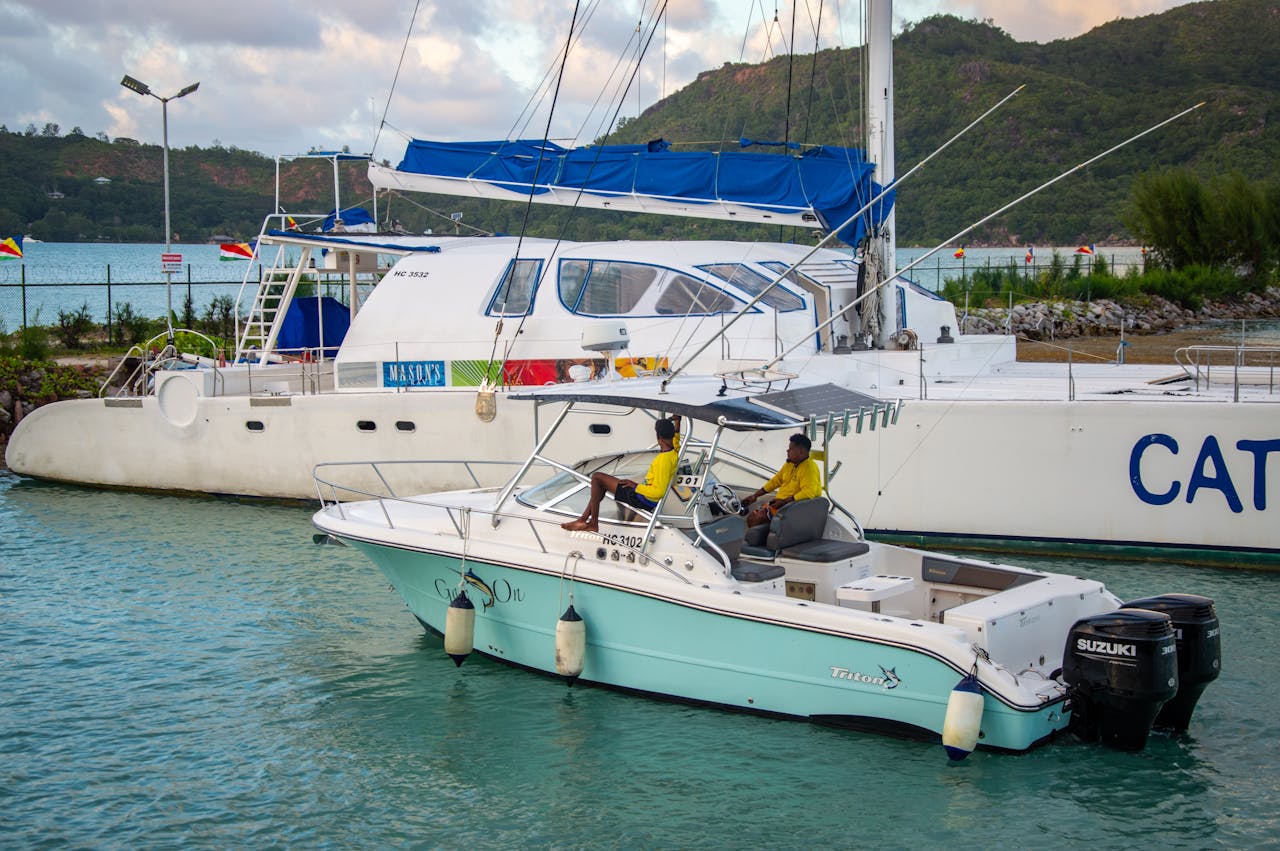 Dual boats anchored in a tropical marina with lush hills in the background.